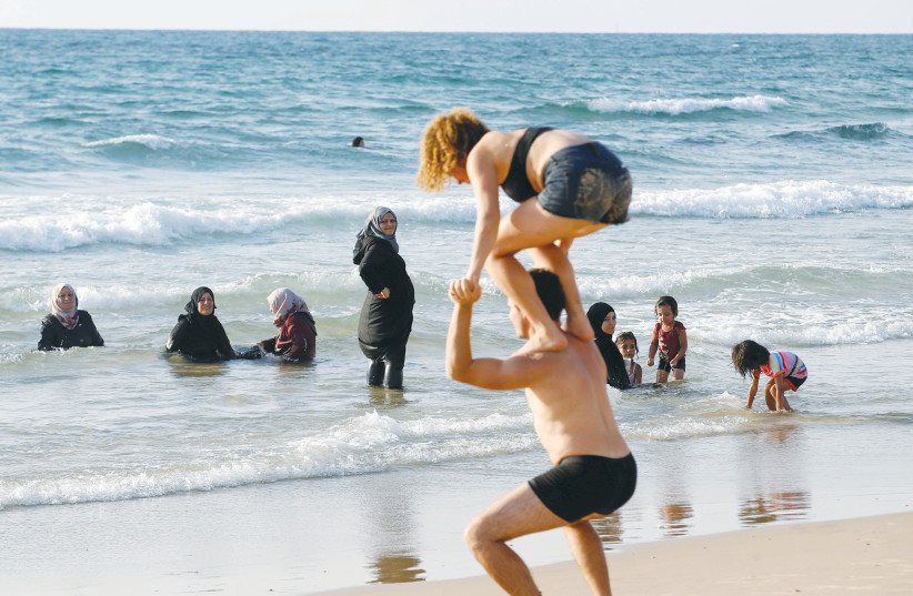  A TEL AVIV beach scene with Muslim women wearing full body coverings enjoying the Mediterranean (Illustrative).  (photo credit: BAZ RATNER/REUTERS)