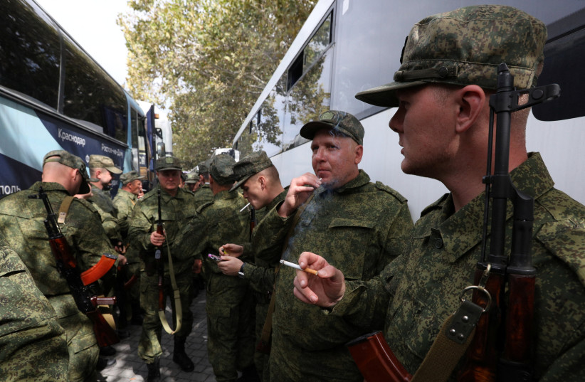  Reservists drafted during the partial mobilisation smoke next to buses as they depart for military bases, in Sevastopol, Crimea September 27, 2022. (photo credit: REUTERS/ALEXEY PAVLISHAK)
