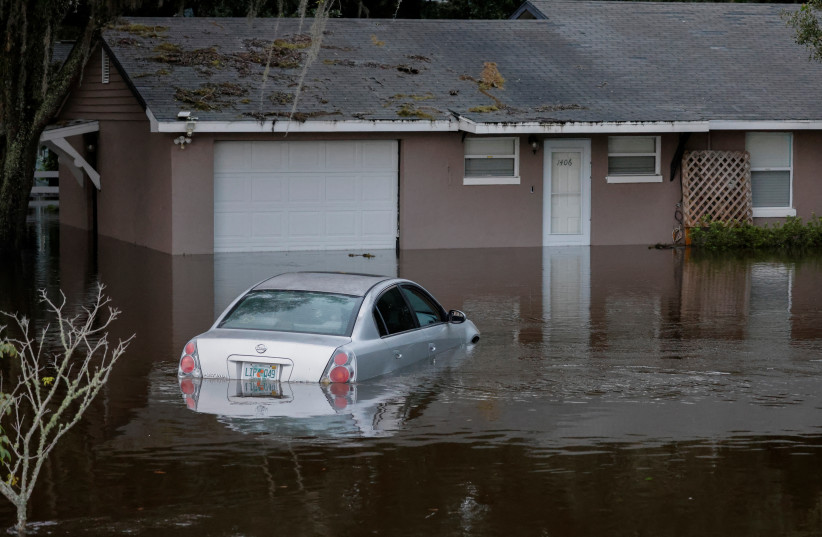 A partially submerged car and home are shown after Hurricane Ian caused widespread damage and flooding in Kissimmee, Florida, US, September 29, 2022. (photo credit: REUTERS/JOE SKIPPER)