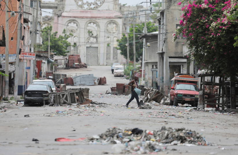  A man walks between road blocks set up by gangs after they waged intense gun battles, shuttering main avenues and a municipal market in the downtown area of the capital, in Port-au-Prince, Haiti July 27, 2022 (credit: REUTERS/RALPH TEDY EROL)