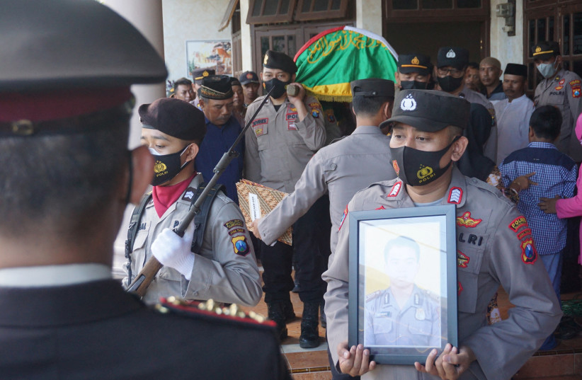  A police officer carries the portrait of Andik Purwanto a police officer who died after a riot and stampede following a soccer match between Arema vs Persebaya in Tambakrejo village, Tulungagung, East Java province, Indonesia, October 2, 2022 (credit: ANTARA FOTO/DESTYAN SUJARWOKO VIA REUTERS)