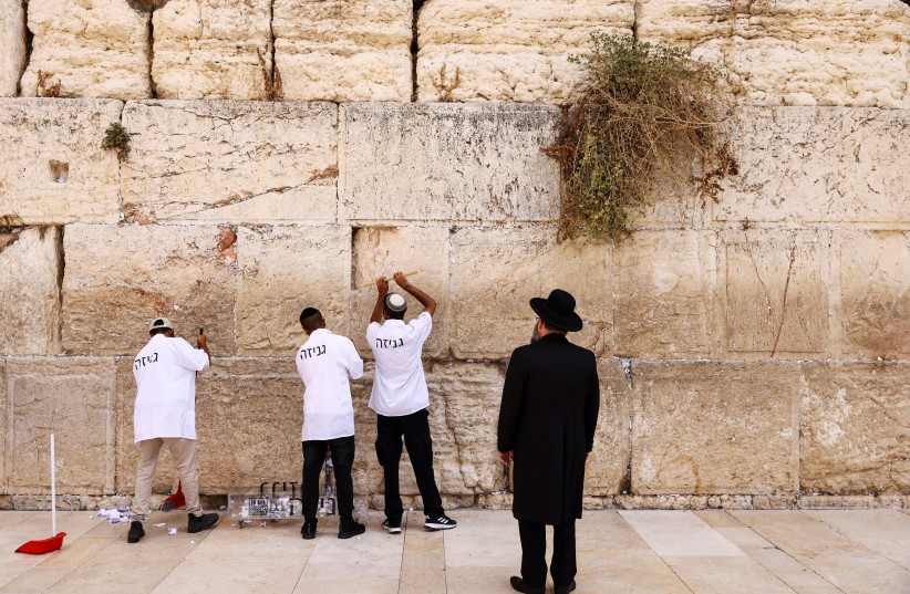  KOTEL RABBI Shmuel Rabinowitz watches as workers clear notes placed in wall cracks, Jerusalem. The book connects physical symbolic objects and prayer. (photo credit: RONEN ZVULUN/REUTERS)