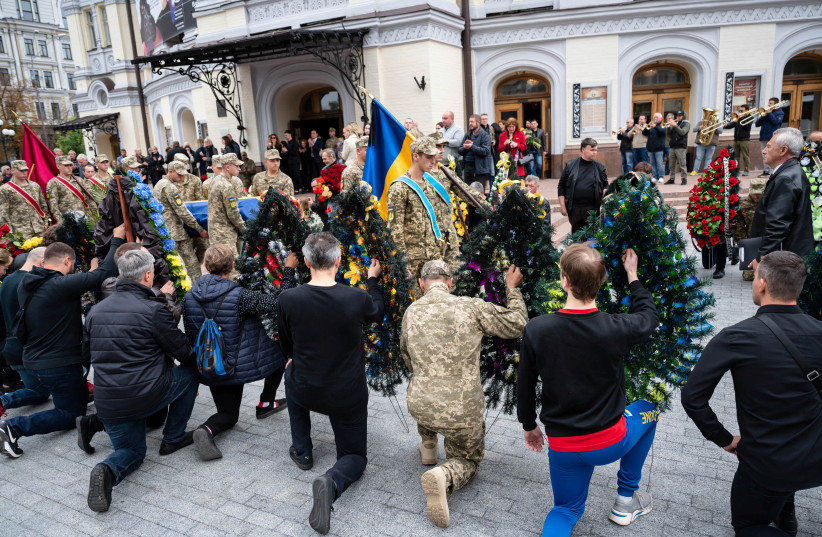 People knee while members of the Honour Guard hold carry a coffin with the body of Ukrainian serviceman and famous ballet dancer Oleksandr Shapoval, during a funeral ceremony outside the National Opera of Ukraine in Kyiv, Ukraine September 17, 2022. (photo credit: Viacheslav Ratynskyi/Reuters)