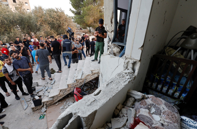  People gather next to a destroyed building during an Israeli raid in Nablus in the West Bank October 5, 2022 (credit: REUTERS/RANEEN SAWAFTA)