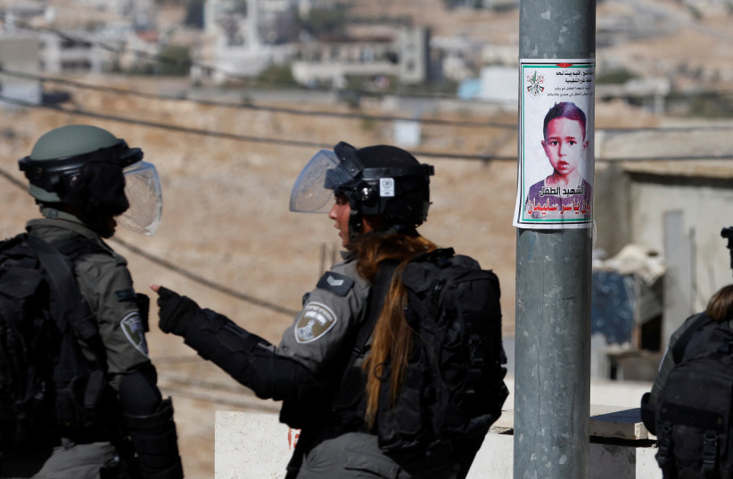  Israeli security forces stand next to a picture of seven-year-old Palestinian boy Rayyan Suleiman (photo credit: MUSSA QAWASMA/REUTERS)