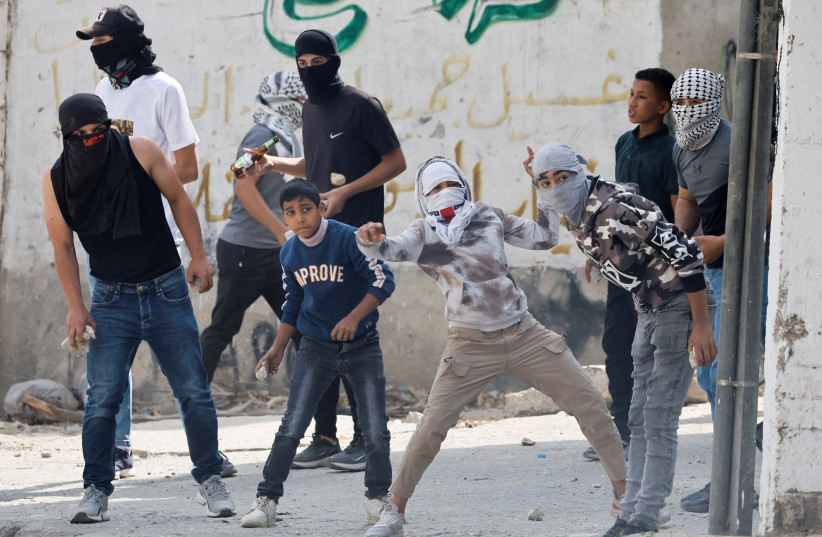  Palestinians clash with Israeli forces following the funeral of Palestinian Osama Adawy, 18, who was killed by Israeli troops during clashes on Wednesday, in Al Aroub camp in the West Bank, October 13, 2022. (credit: MUSSA QAWASMA/REUTERS)