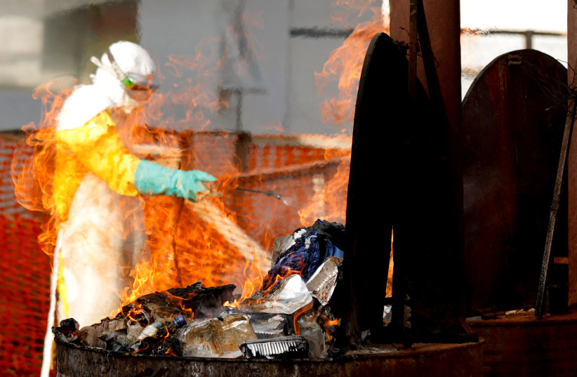  A health worker burns food waste of Ebola patients at an Ebola treatment center (ETC) in Katwa, near Butembo, in the Democratic Republic of Congo, October 5, 2019 (photo credit: REUTERS/ZOHRA BENSEMRA)