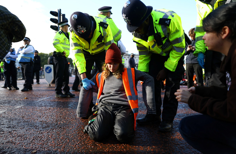  Police officers detain a demonstrator during a 'Just Stop Oil' protest outside Buckingham Palace, in London, Britain October 10, 2022.  (credit: REUTERS/HANNAH MCKAY)
