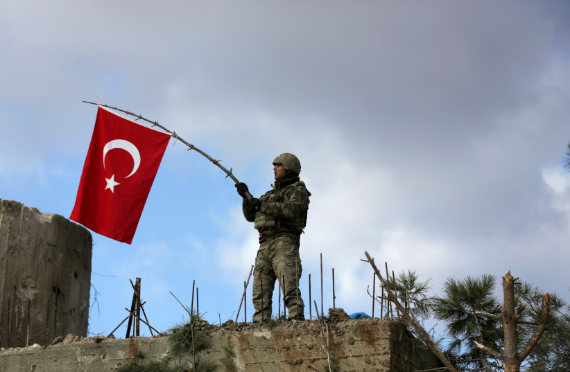   A Turkish soldier waves a flag on Mount Barsaya, northeast of Afrin, Syria January 28 ,2018.  (credit: KHALIL ASHAWI / REUTERS)
