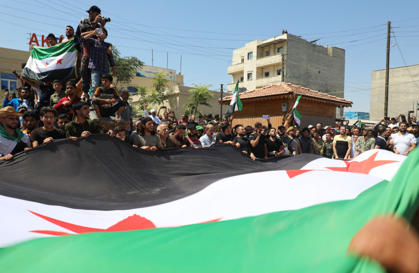  Demonstrators hold a Syrian opposition flag during a protest against Turkish Foreign Minister Mevlut Cavusoglu's comments on reconciliation of the opposition with the Syrian government, in the rebel-held city of Azaz, Syria August 12, 2022.  (photo credit: REUTERS/MAHMOUD HASSANO)