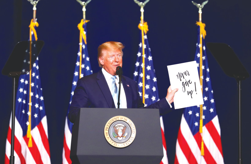  THEN-US president Donald Trump holds up a sign which reads ‘Never give up!’ as he delivers a speech to evangelical supporters in Miami, 2020. Jews should be more like ‘our wonderful evangelicals,’ Trump posted on Sunday.  (photo credit: EVA MARIE UZCATEGUI/ REUTERS)