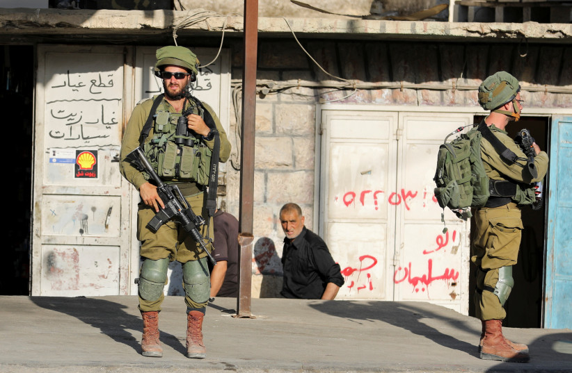  Israeli soldiers stand while stationed outside a Palestinian shop in Huwara, the West Bank, May 26, 2022. (credit: RANEEN SAWAFTA/ REUTERS)