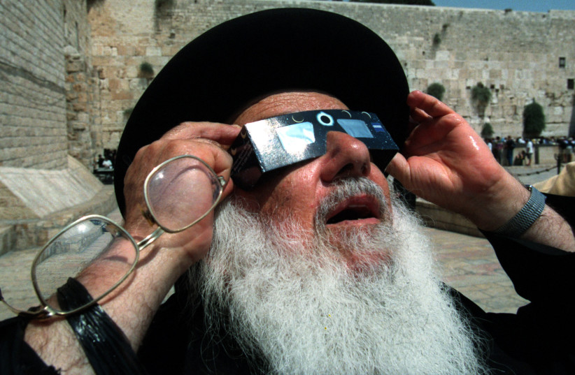  An ultra-Orthodox Jewish rabbi holds up a pair of special glasses as he views the last solar eclipse of the millennium August 11 in front of the Western Wall. August, 1999 (photo credit: JWH/KM via Reuters)