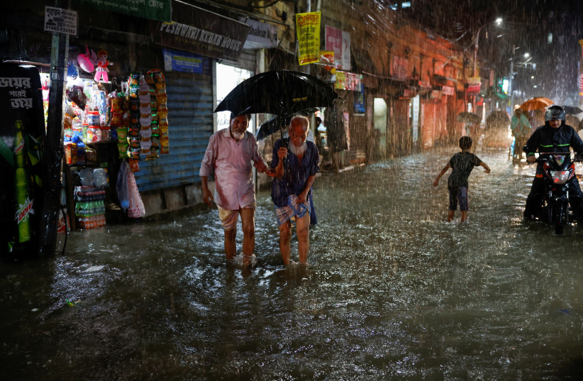  People wade through a flooded street amid continuous rain before the Cyclone Sitrang hits the country in Dhaka, Bangladesh, October 24, 2022. (photo credit: REUTERS/MOHAMMAD PONIR HOSSAIN)