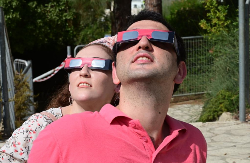  Israelis are seen looking at the partial solar eclipse in the sky above Givatayim with protective eyeware, on October 25, 2022. (photo credit: AVSHALOM SASSONI/MAARIV)
