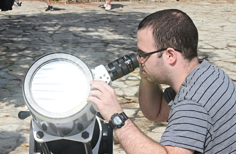  An Israeli is seen using protective lensing to view the partial solar eclipse in Givatayim, on October 25, 2022. (credit: AVSHALOM SASSONI/MAARIV)