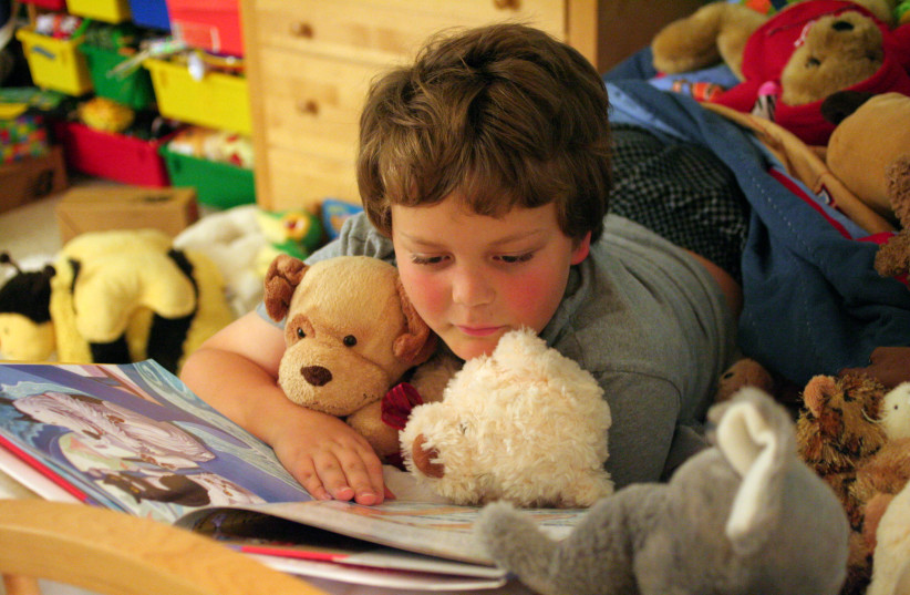  A child reading comics with soft toy beside (credit: Wikimedia Commons)