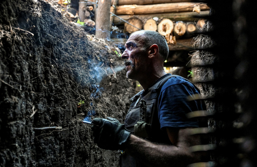  Ukrainian service member smokes in a trench at a position in a frontline in Zaporizhzhia region (photo credit: REUTERS)