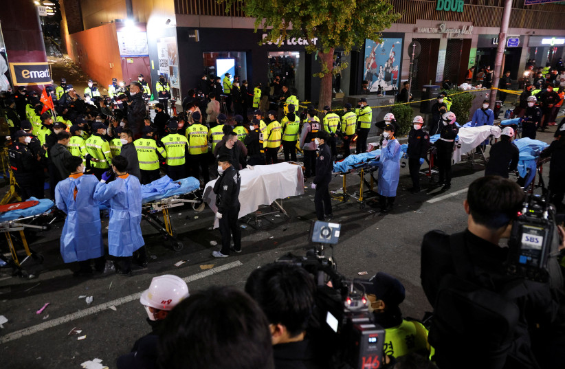  Rescue team members wait with stretchers to remove bodies from the scene where dozens of people were injured in a stampede during a Halloween festival in Seoul, South Korea (photo credit: REUTERS)