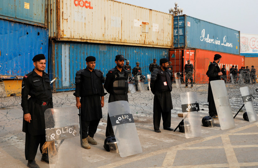 Police officers and paramilitary soldiers with riot gear stand near shipping containers used to block the area at the Red Zone, ahead of the planned true freedom march by the former Prime Minister Imran Khan to pressure the government to announce new elections, in Islamabad, Pakistan. (credit: REUTERS/AKHTAR SOOMRO)
