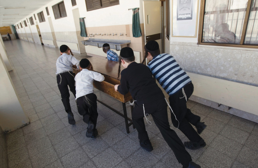  ULTRA-ORTHODOX children push a desk in a hallway of a school in Jerusalem’s Mea Shearim neighborhood. (credit: RONEN ZVULUN/REUTERS)