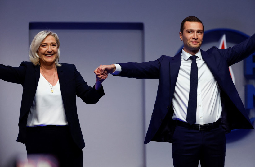  Jordan Bardella, newly-elected President of the French far-right National Rally (Rassemblement National - RN) party, holds the hand of Marine Le Pen, member of parliament and member of the French far-right National Rally party, after the results during the National Rally party's Congress in Paris.  (photo credit: REUTERS/CHRISTIAN HARTMANN)