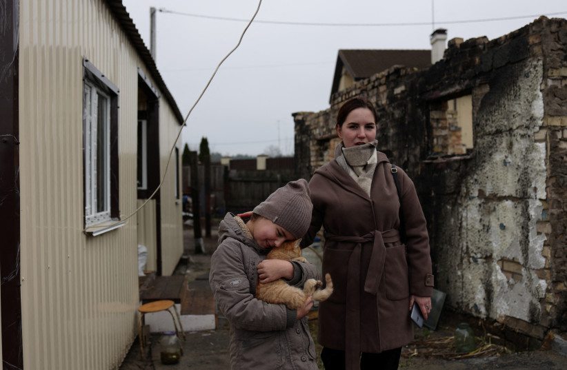  Kateryna Tyshchenko, accompanied by her 9-year-old half-sister Yuliia Zaika, stands outside her prefabricated accommodation which was built next to her destroyed house in the village of Moshchun near Kyiv (photo credit: REUTERS)