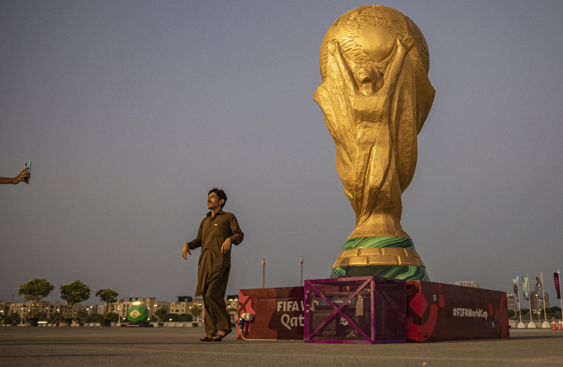   A man poses with a replica of the World Cup outside Lusail Stadium ahead of the World Cup (credit: REUTERS/MARKO DJURICA)
