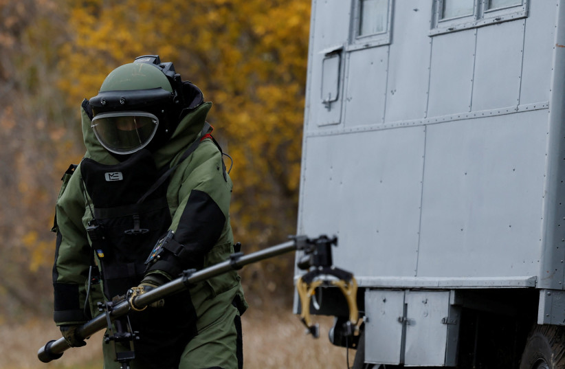  A Ukrainian service member, wearing protective gear, demonstrates using equipment to detect mines in a field, amid Russia's invasion, in the Kharkiv region of Ukraine October 27, 2022. (photo credit: CLODAGH KILCOYNE/REUTERS)