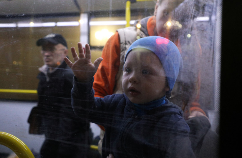  A child looks through the bus window as civilians evacuated from the Russian-controlled part of Kherson region of Ukraine arrive at a local railway station in the town of Dzhankoi, Crimea November 10, 2022. (credit: REUTERS/ALEXEY PAVLISHAK)