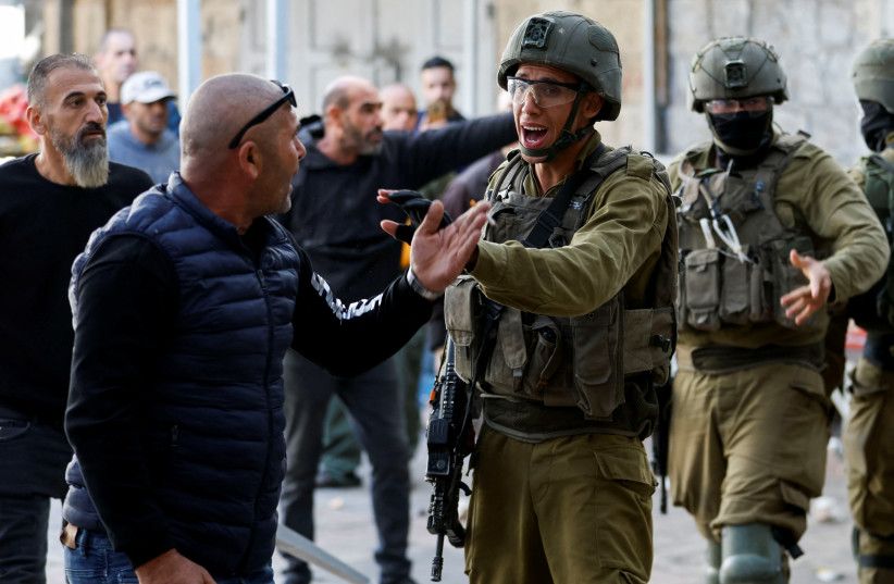  An Israeli soldier gestures during a scuffle between Palestinians and Israeli settlers in Hebron in the West Bank November 19, 2022. (credit: MUSSA QAWASMA/REUTERS)