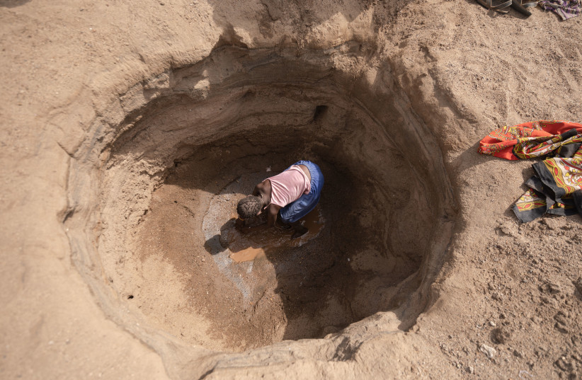 A child digs for water in dry riverbeds in Turkana West, Kenya. (photo credit: IsraAID/Lameck Ododo)