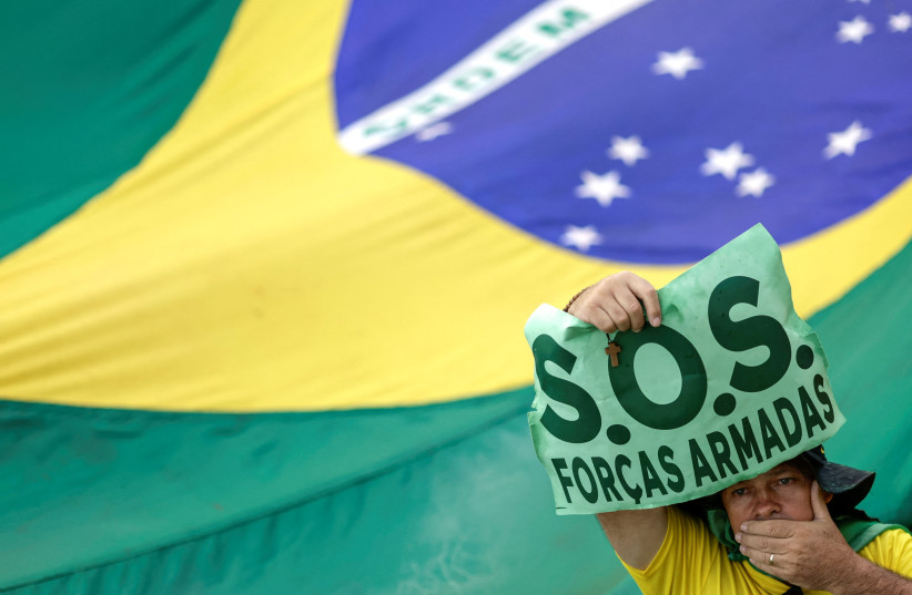  A man uses his hand to cover his mouth during a protest held by supporters of Brazil's President Jair Bolsonaro against President-elect Luiz Inacio Lula da Silva, who won a third term following the presidential election run-off, at the Army Headquarters in Brasilia, Brazil, November 15, 2022 (credit: REUTERS/UESLEI MARCELINO)