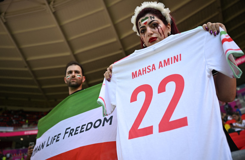  Iran fans hold a 'Women Life Freedom' Iran flag and a t-shit in memory of Mahsa Amini, inside the stadium before the match, November 25, 2022. (credit: REUTERS/DYLAN MARTINEZ)
