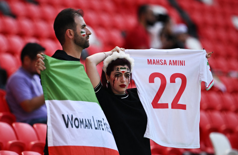  Iran fans hold a 'Women Life Freedom' Iran flag and a replica shirt in memory of Mahsa Amini, inside the stadium before the match (photo credit: DYLAN MARTINEZ/REUTERS)