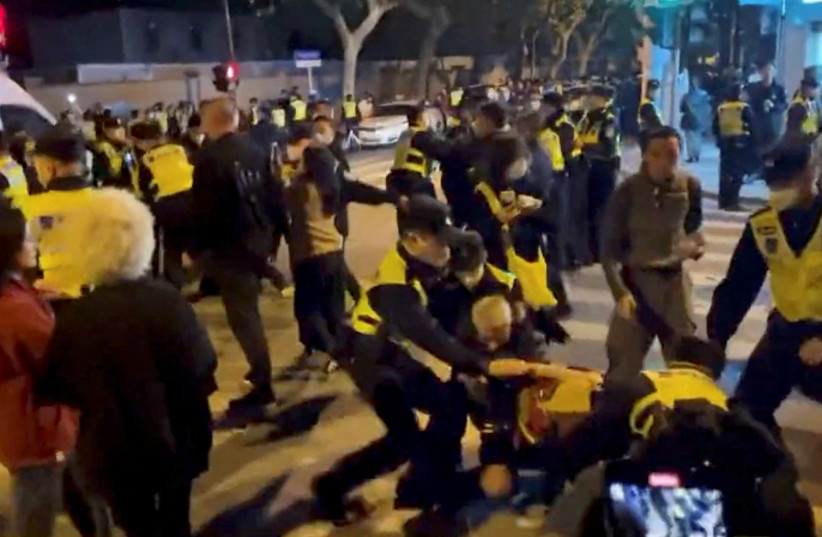 Police officers detain people during a protest against coronavirus disease (COVID-19) curbs at the site of a candlelight vigil for victims of the Urumqi fire, in Shanghai, China in this screengrab obtained from a video released on November 27, 2022. (credit: VIDEO OBTAINED BY REUTERS/VIA REUTERS)