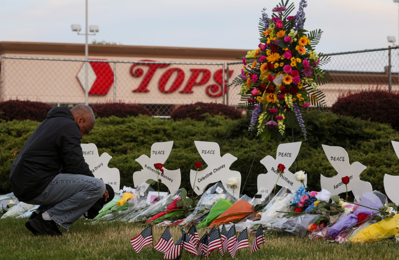  A man prays at a memorial at the scene of a weekend shooting at a Tops supermarket in Buffalo, New York, U.S. May 19, 2022 (credit: REUTERS/BRENDAN MCDERMID/FILE PHOTO)