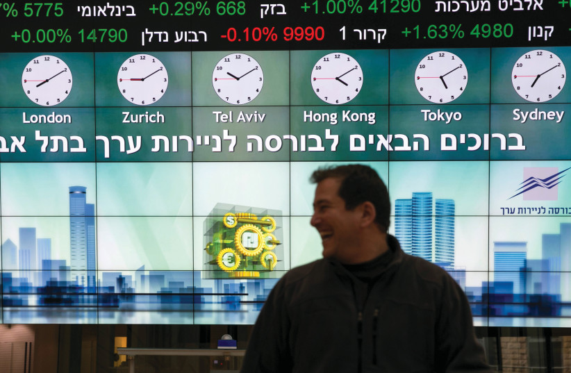  A man stands in front of an electronic board displaying market data at the Tel Aviv Stock Exchange. (photo credit: BAZ RATNER/REUTERS)