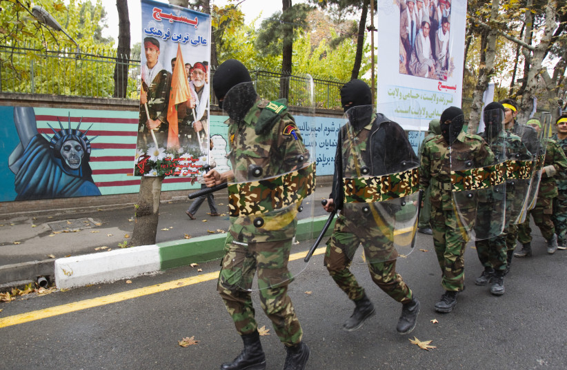  Masked members of the Basij militia march during a military parade to mark Basij week in front of the former U.S. embassy in Tehran November 25, 2011. (credit: RAHEB HOMAVANDI/REUTERS)