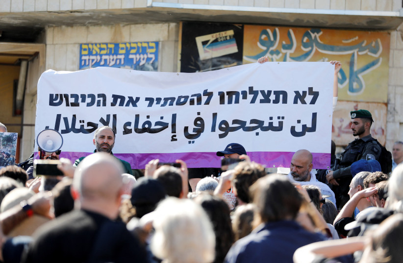  A banner is seen as Israeli activists take part in a tour for a group called Breaking the Silence, in Hebron in the West Bank December 2, 2022. The banner reads: ''You will not succeed in hiding occupation.'' (credit: REUTERS/MUSSA QAWASMA)
