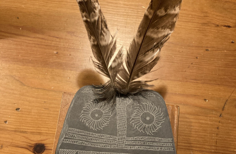 Replica of the Valencina Slate Plaque with inserted owl feathers on the two drilled holes at the top of the plaque. (credit: JUAN J. NEGRO)