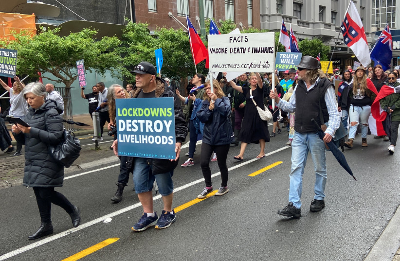  Anti-vaccine mandate protesters march through the city and gather in front of the parliament in Wellington, New Zealand, December 16, 2021. (photo credit: REUTERS/PRAVEEN MENON)