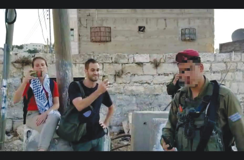  A SOLDIER (face blurred) is confronted by hostile activists in Hebron. (photo credit: IM TIRTZU)