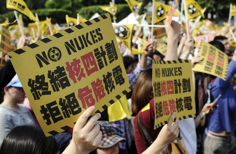 Anti-nuclear activists hold up placards and wave flags during a protest in Taipei, Taiwan March 9, 2013.The Chinese characters on the placard reads, ''To stop the fourth nuclear power plant project. Reject dangerous nuclear power.''   (credit: REUTERS/TIMOTHY SIM)