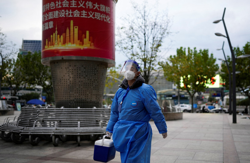  A worker in protective suit walks, as coronavirus disease (COVID-19) outbreaks continue in Shanghai, China, December 5, 2022. (photo credit: REUTERS/ALY SONG)