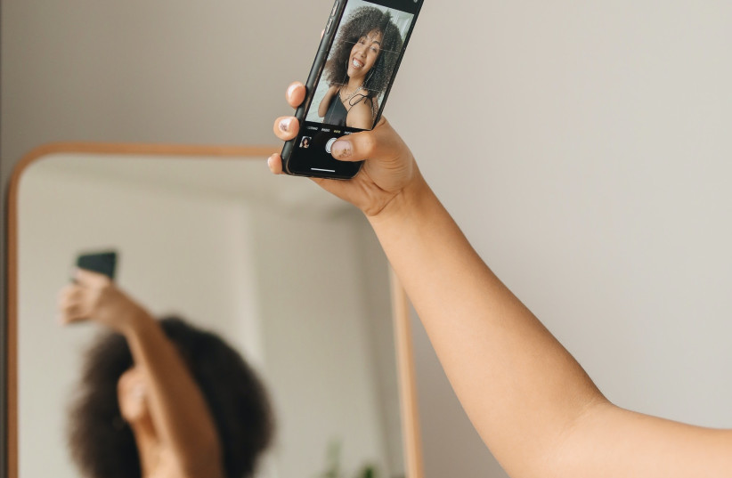  Woman taking photo while looking in mirror (illustrative) (photo credit: PEXELS)