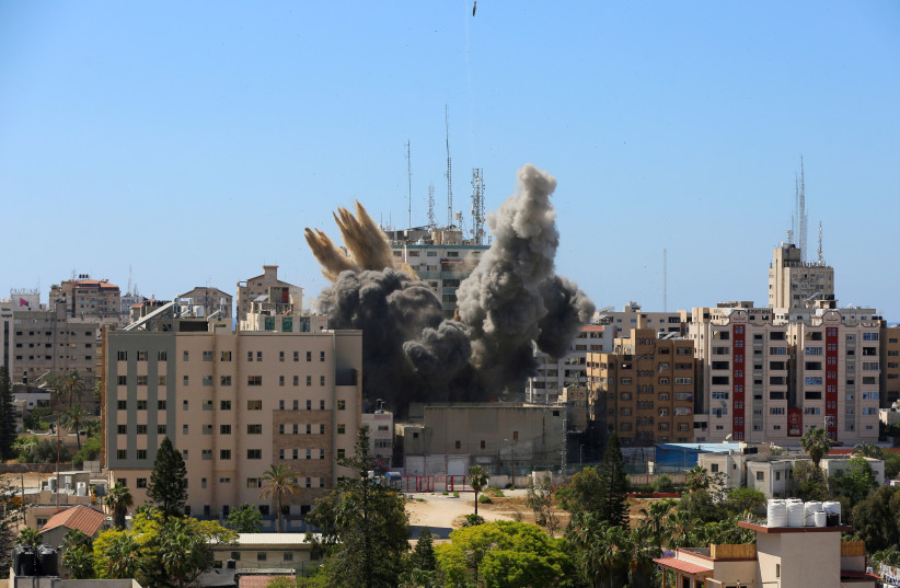 Un missile tombe alors que de la fumée monte près d'une tour abritant AP, les bureaux d'Al Jazeera (C) lors de frappes de missiles israéliens dans la ville de Gaza, le 15 mai 2021. (Crédit : REUTERS/ASHRAF ABU AMRAH)