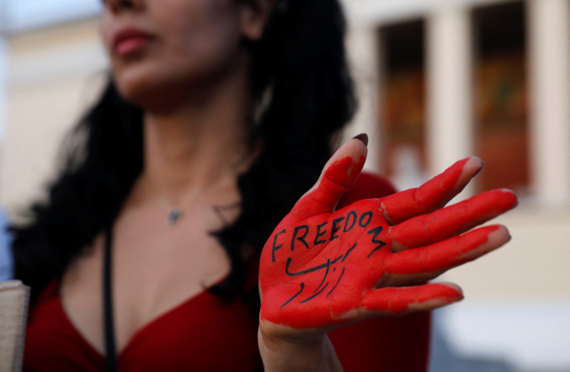  A woman with her hand painted with the word "Freedom" takes part in a protest following the death of Mahsa Amini, in Athens, Greece, October 1, 2022. (photo credit: REUTERS/COSTAS BALTAS)