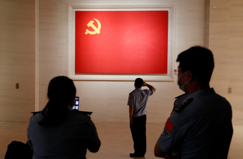  A police officer poses for a picture in front of a Chinese Communist Party flag at the Museum of the Communist Party of China in Beijing, China September 3, 2022.  (credit: REUTERS/FLORENCE LO)