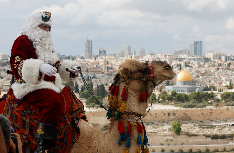  Issa Kassissieh wears a Santa Claus costume as he rides a camel during Christmas season on the Mount of Olives in Jerusalem. The Dome of the Rock is seen in the background. December 6, 2022. (credit: REUTERS/AMMAR AWAD)
